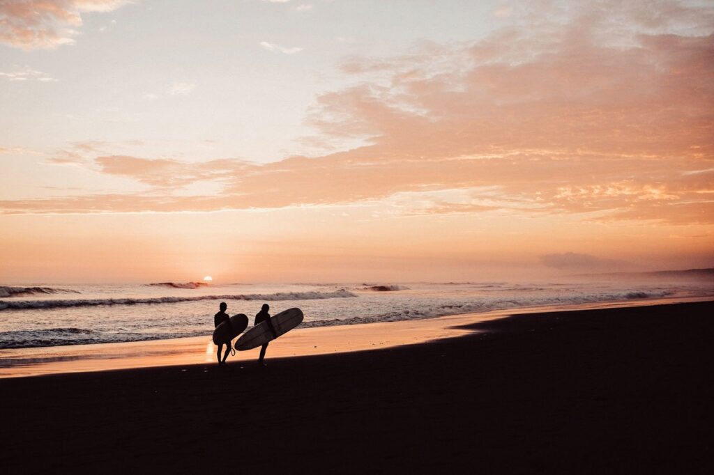 2 surfers infront of sea and sunrise