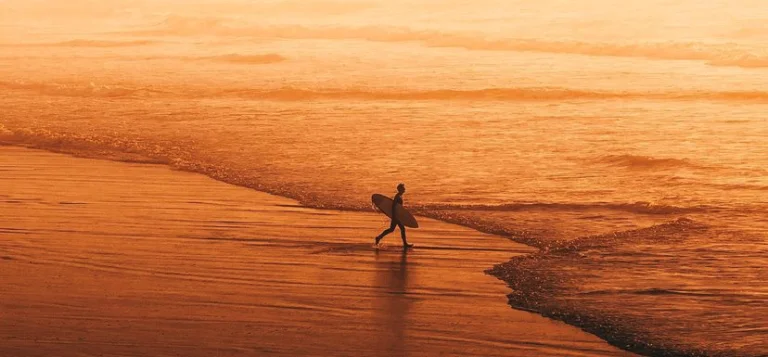 Surfer entering the sea at sunset in San Sebastian, Surf trips from San Sebastian